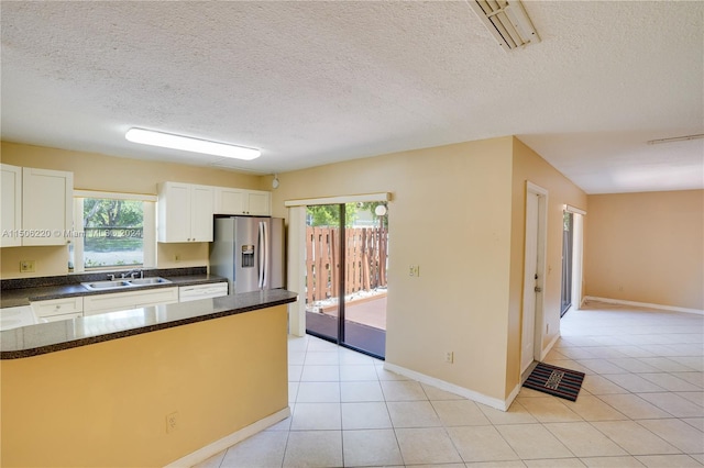 kitchen with light tile patterned flooring, white cabinetry, sink, stainless steel fridge with ice dispenser, and a healthy amount of sunlight