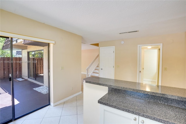 kitchen with white cabinetry, a textured ceiling, and light tile patterned floors