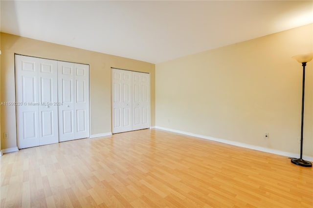 unfurnished bedroom featuring light hardwood / wood-style floors and two closets