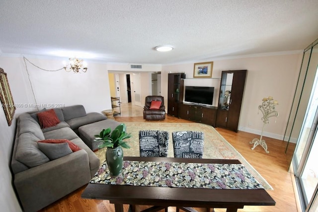 living room with a textured ceiling, crown molding, a notable chandelier, and light hardwood / wood-style floors