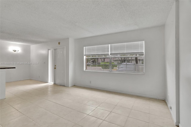 empty room featuring a textured ceiling and light tile floors