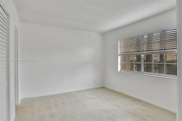 spare room featuring a textured ceiling and light tile floors