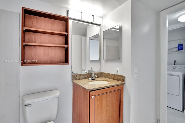 bathroom featuring washer / dryer, toilet, and vanity with extensive cabinet space