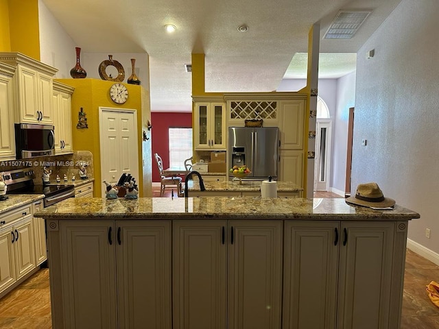 kitchen featuring appliances with stainless steel finishes, cream cabinetry, and an island with sink