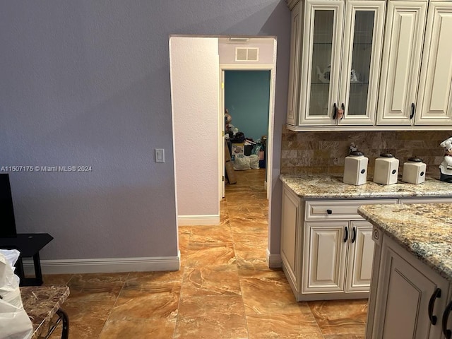 kitchen with decorative backsplash, light stone counters, and light tile patterned floors