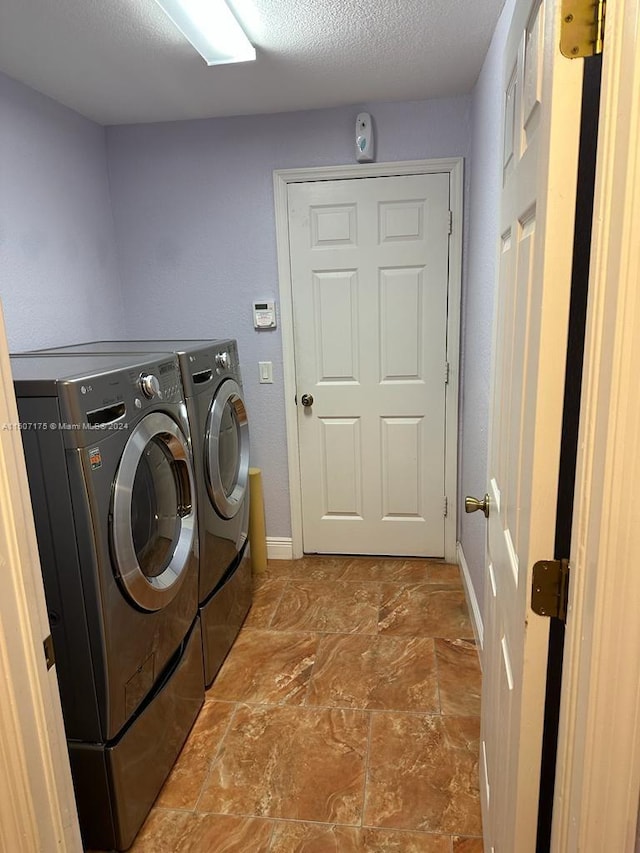 laundry room featuring light tile patterned flooring, washer and clothes dryer, and a textured ceiling