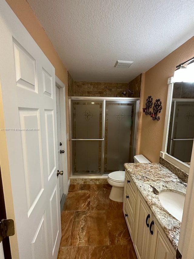 bathroom with a shower with door, toilet, tile patterned flooring, vanity, and a textured ceiling