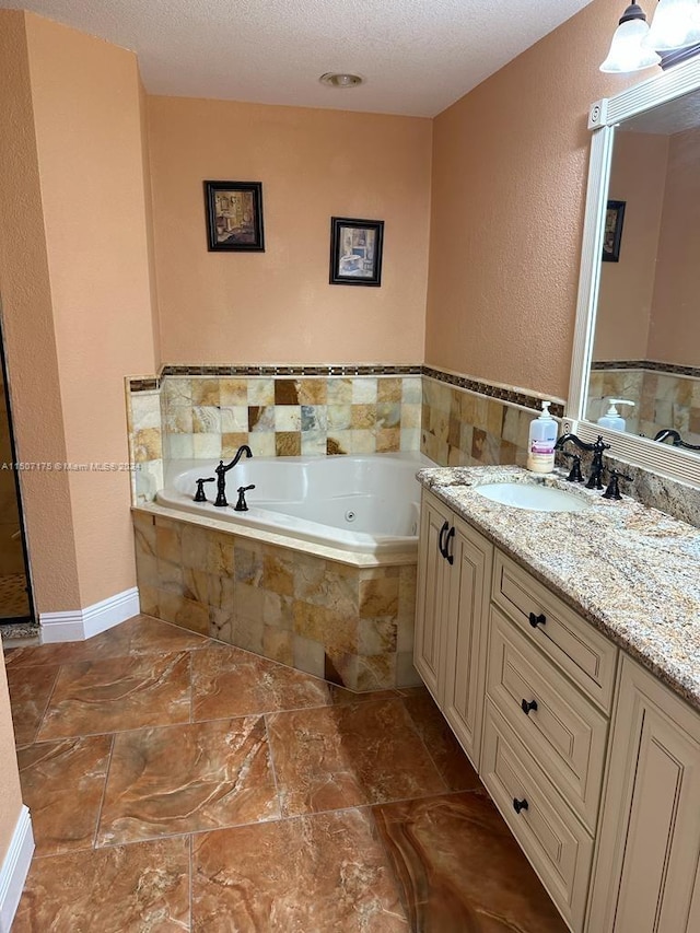 bathroom with a textured ceiling, tiled tub, vanity, and tile patterned floors