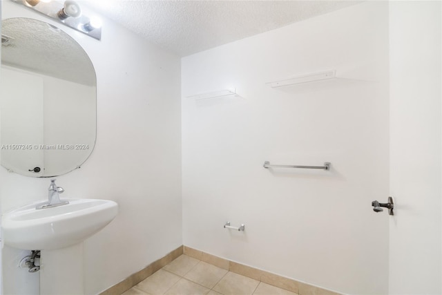 bathroom with tile patterned floors, baseboards, and a textured ceiling
