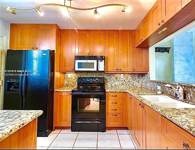 kitchen with rail lighting, black appliances, and light stone countertops