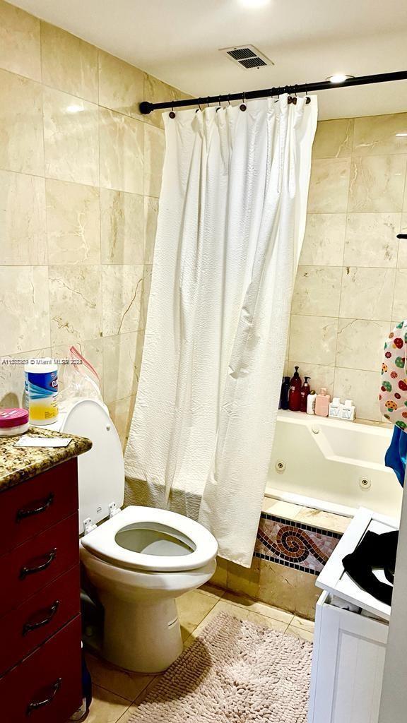 full bathroom with toilet, tile walls, tile patterned floors, and vanity