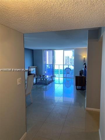 hallway with a textured ceiling and tile patterned floors