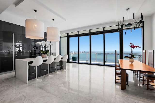 kitchen featuring a kitchen breakfast bar, a water view, decorative light fixtures, and light tile floors