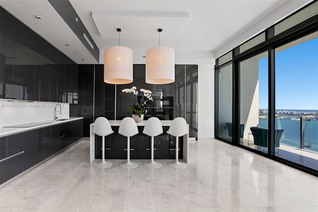 kitchen with pendant lighting, a kitchen breakfast bar, light tile flooring, a water view, and a notable chandelier