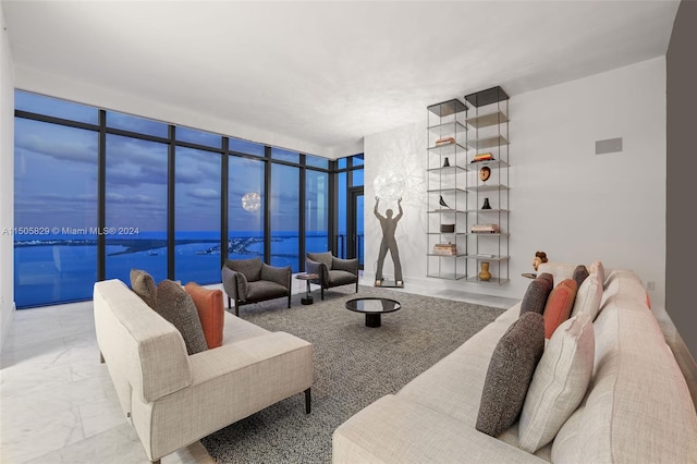 tiled living room featuring a water view and a wall of windows