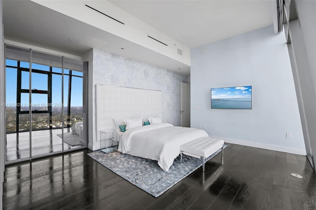 bedroom featuring floor to ceiling windows, dark hardwood / wood-style floors, and access to exterior