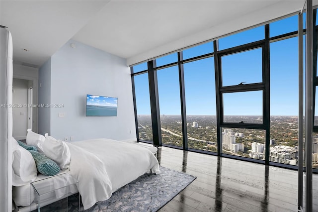 bedroom with expansive windows, hardwood / wood-style floors, and multiple windows