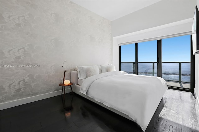 bedroom featuring dark hardwood / wood-style floors and a water view