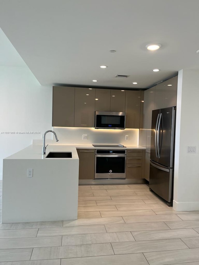 kitchen featuring appliances with stainless steel finishes, backsplash, gray cabinets, and sink