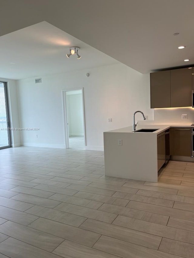 kitchen featuring dishwasher, sink, light tile patterned flooring, oven, and kitchen peninsula