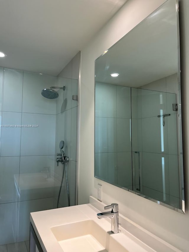 bathroom with tiled shower and vanity