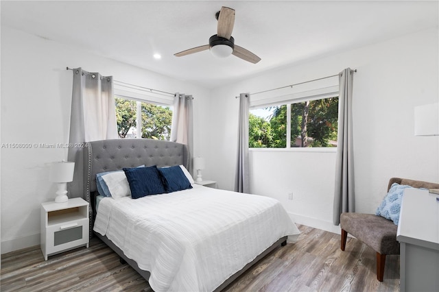 bedroom featuring ceiling fan, multiple windows, and hardwood / wood-style floors