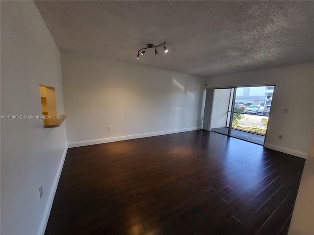 unfurnished room with track lighting, a textured ceiling, and dark hardwood / wood-style flooring