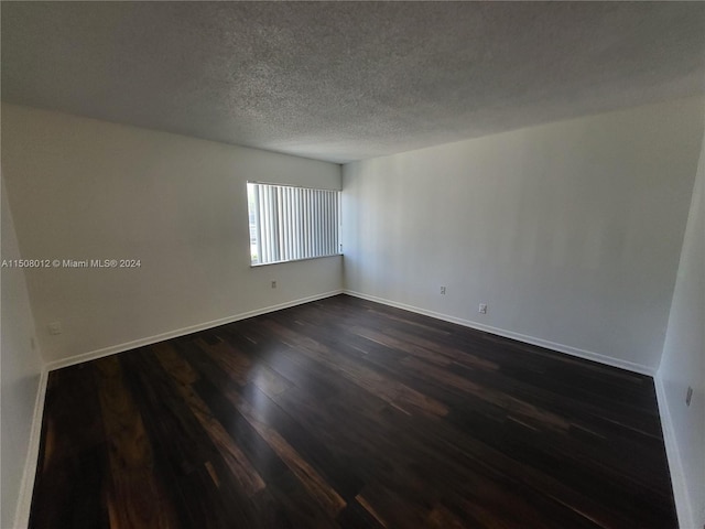 unfurnished room featuring a textured ceiling and dark wood-type flooring