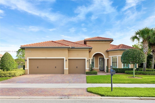 mediterranean / spanish home featuring a garage and a front lawn