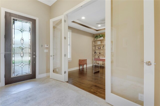 foyer entrance with a raised ceiling, french doors, and light hardwood / wood-style flooring