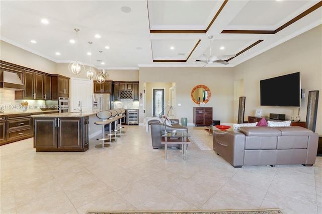 living room with ceiling fan, sink, coffered ceiling, light tile patterned flooring, and ornamental molding