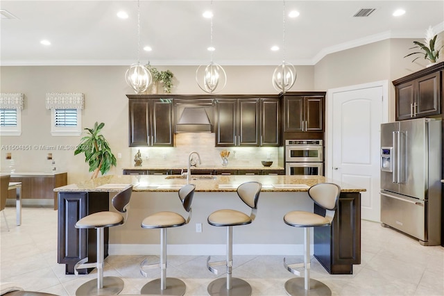 kitchen with hanging light fixtures, an island with sink, stainless steel appliances, and sink