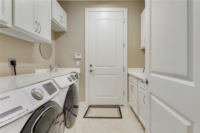 laundry room with washing machine and clothes dryer, light tile patterned floors, and cabinets