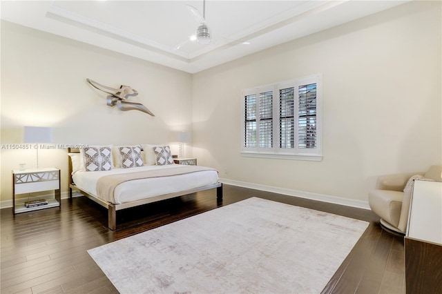 bedroom with dark hardwood / wood-style flooring and a tray ceiling