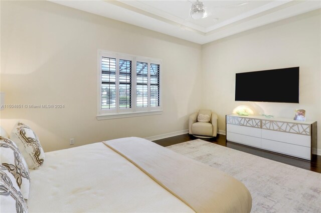 bedroom with dark hardwood / wood-style floors and a raised ceiling