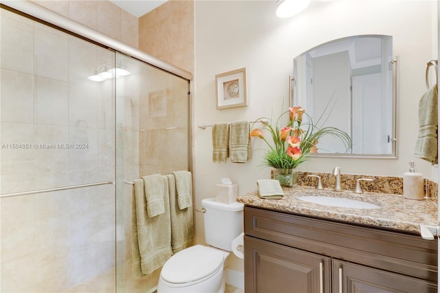 bathroom featuring vanity, toilet, and a shower with door