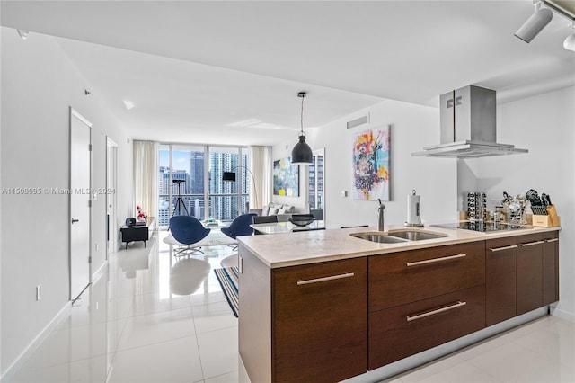 kitchen featuring island range hood, expansive windows, light tile floors, and sink