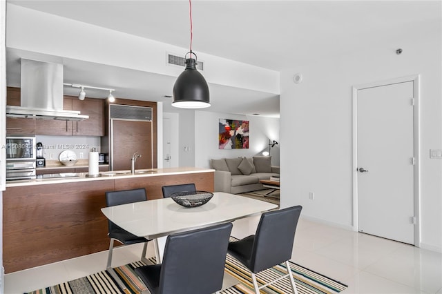 dining area featuring light tile floors, rail lighting, and sink