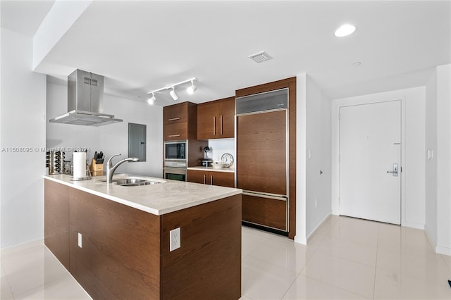 kitchen featuring built in appliances, light tile floors, fume extractor, rail lighting, and sink