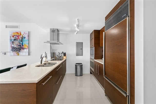 kitchen featuring paneled built in fridge, light tile flooring, track lighting, sink, and island range hood