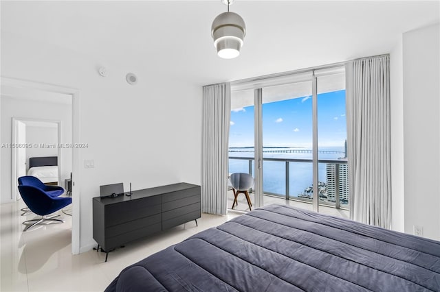 tiled bedroom with expansive windows, access to exterior, and a water view