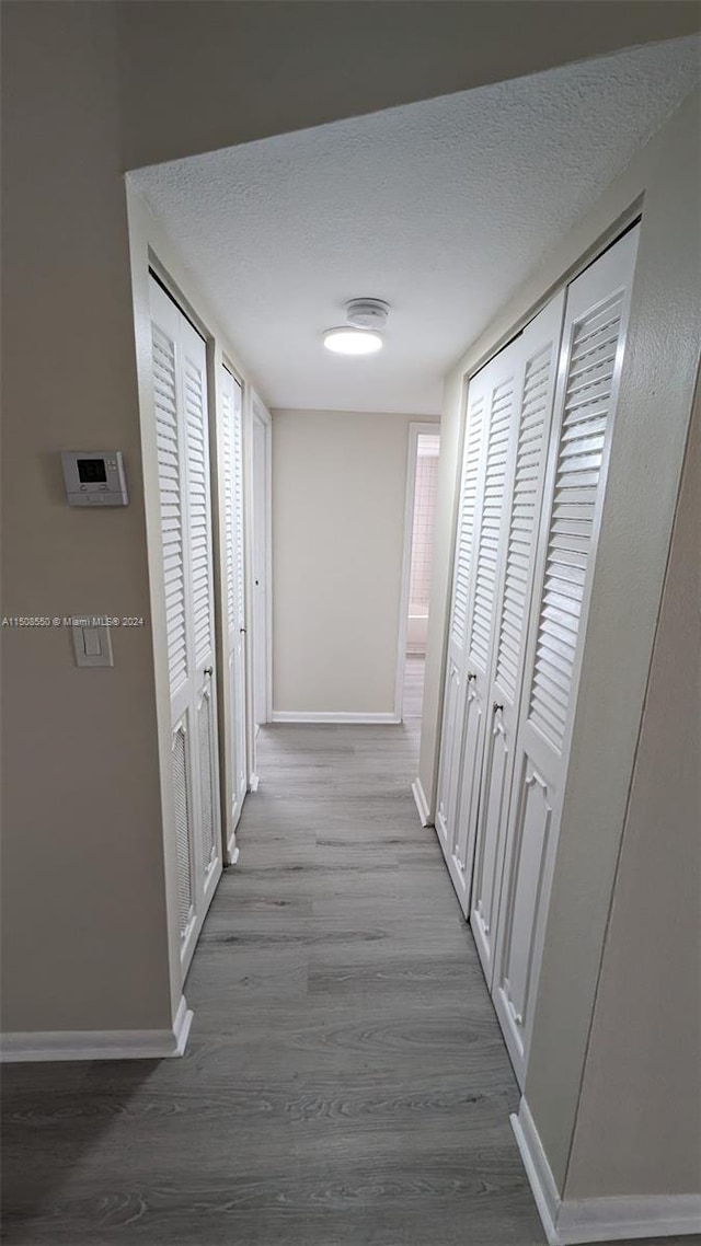 corridor featuring a textured ceiling and hardwood / wood-style flooring