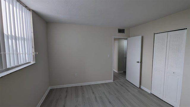 unfurnished bedroom with a closet and light hardwood / wood-style flooring