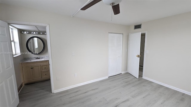 unfurnished bedroom with connected bathroom, light hardwood / wood-style floors, ceiling fan, a closet, and sink