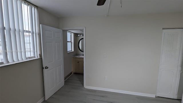 unfurnished bedroom featuring multiple windows, a closet, ceiling fan, and light hardwood / wood-style flooring