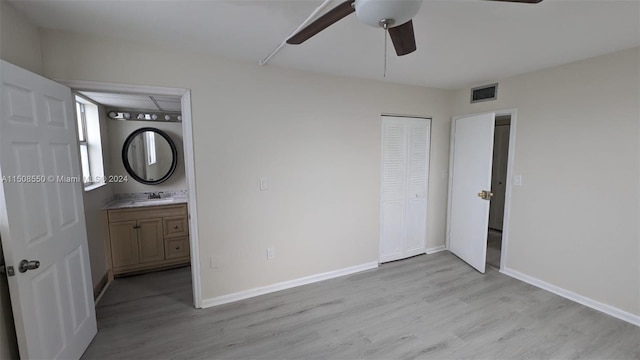 unfurnished bedroom with ceiling fan, a closet, ensuite bathroom, light wood-type flooring, and sink