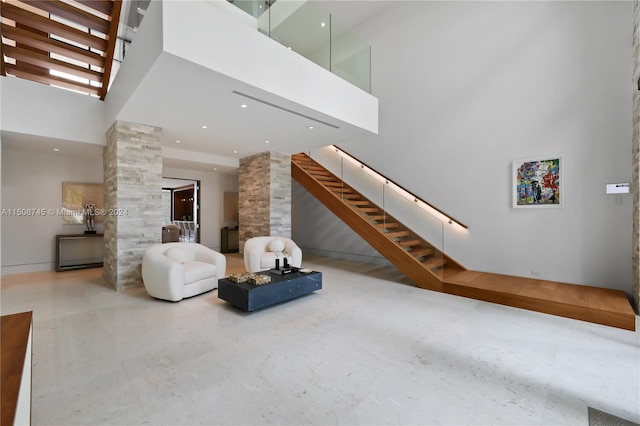 living room with a towering ceiling, ornate columns, and concrete floors