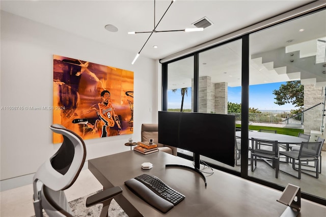 home office with an inviting chandelier, a wall of windows, and concrete flooring