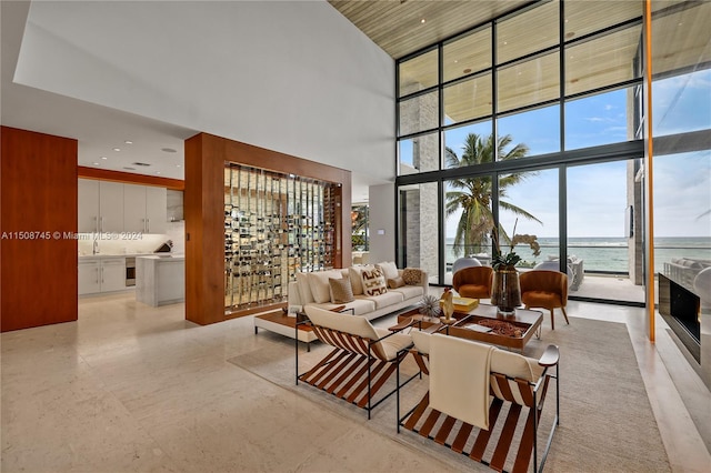 living room with a high end fireplace, sink, expansive windows, a high ceiling, and a water view