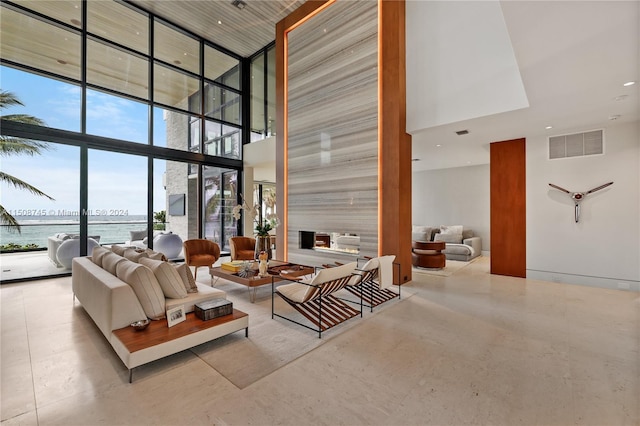 living room featuring a water view, a wall of windows, and a high ceiling